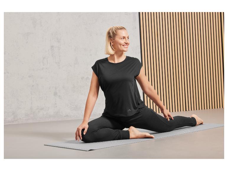 Eine Frau trägt schwarze Yoga-Leggings und ein Top während einer Yoga-Sitzung.