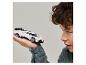 Ein junger Mann betrachtet ein weißes Miniatur-Rennauto, das er in der Hand hält.
