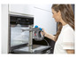 Eine Frau reinigt einen Backofen mit einem Bissell SteamShot Dampfreiniger.