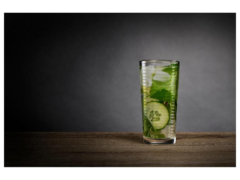 Erfrischendes Wasser mit Gurke, Minze und Eis in einem Glas auf einem Holztisch.