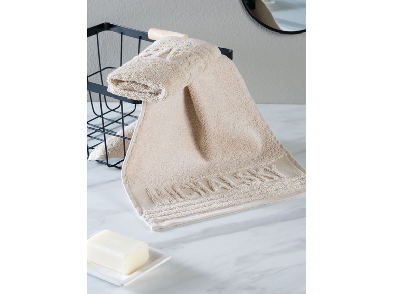 Beigefarbenes Handtuch in einem schwarzen Korb, neben einer Seife.