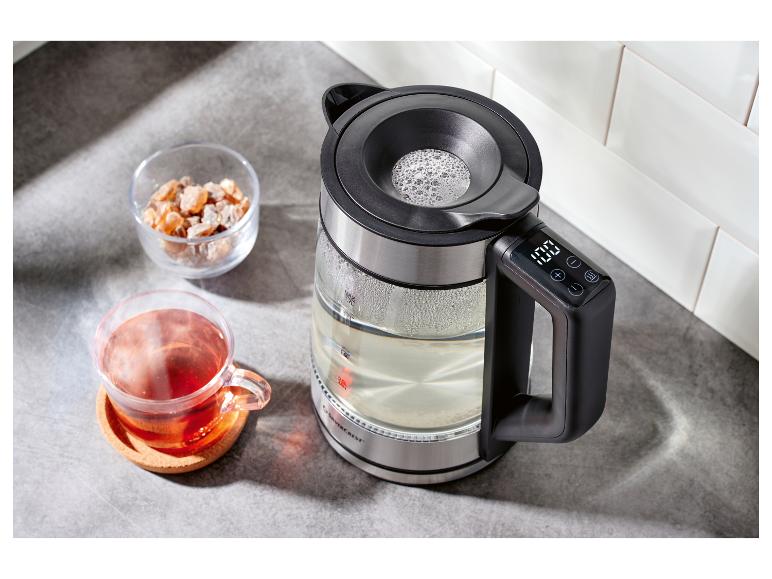 Glaswasserkocher mit Digitalanzeige, neben einer Tasse Tee und Zucker.