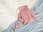 Ein rosa Hoodie, ein rosa Tintenfisch und ein gestreiftes Spielzeug auf einer blauen und weißen Decke.