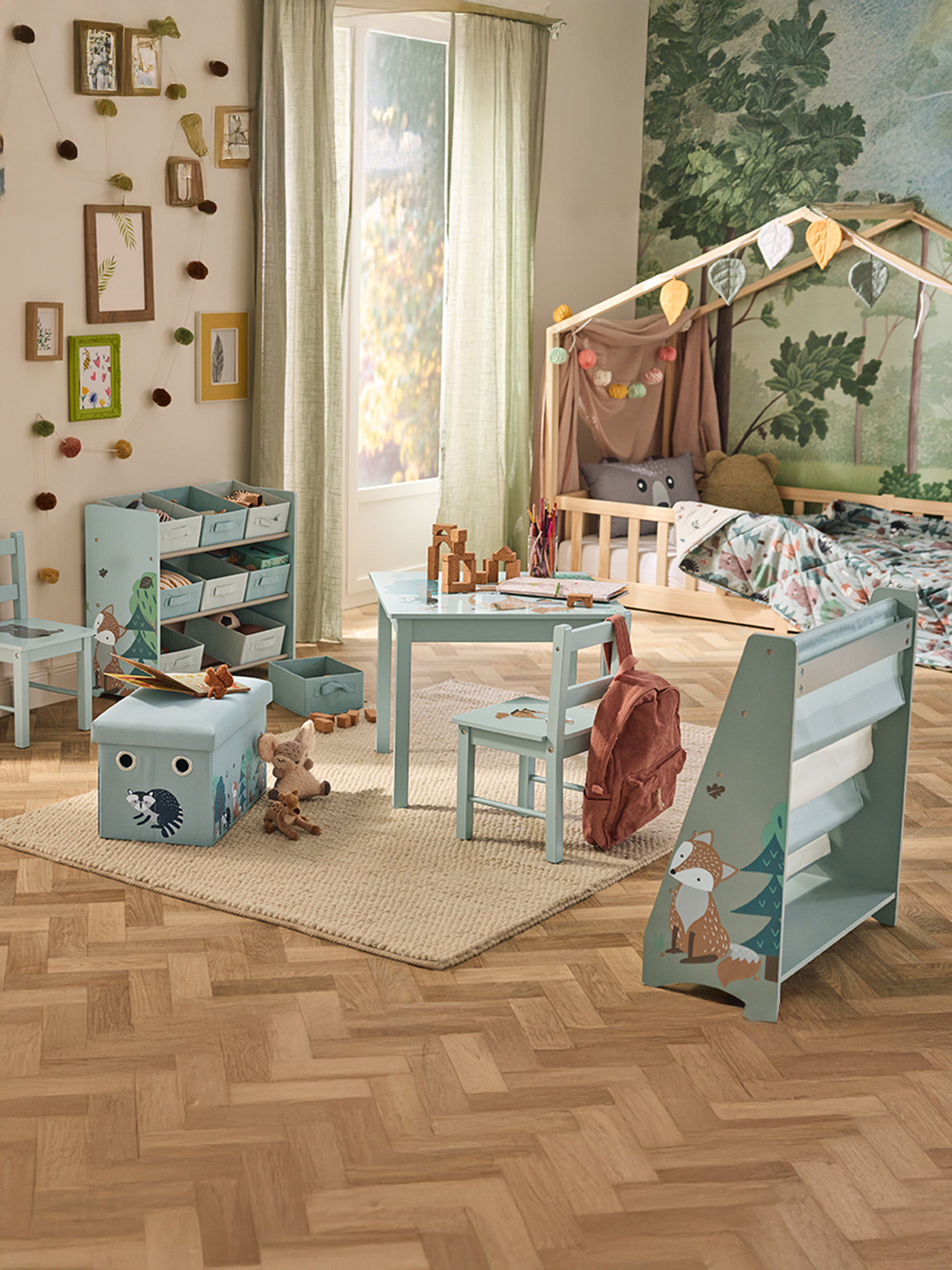 Ein Kinderzimmer im Waldthema, mit Bett, Tisch, Stühlen und Aufbewahrungsmöbeln.