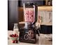 Mixer bereitet Beerensmoothie auf Küchenarbeitsplatte zu, daneben Beeren und Milch.