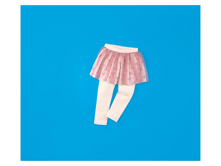 Kleinkind-Mädchen-Tutu-Rock in Rosa mit Regenbogen-Print über cremefarbenen Leggings auf blauem Hintergrund.