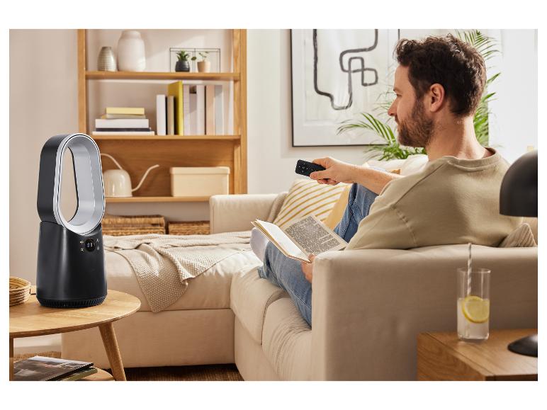 Ein Mann entspannt sich auf dem Sofa und steuert einen Dyson-Ventilator ohne Blätter mit einer Fernbedienung.