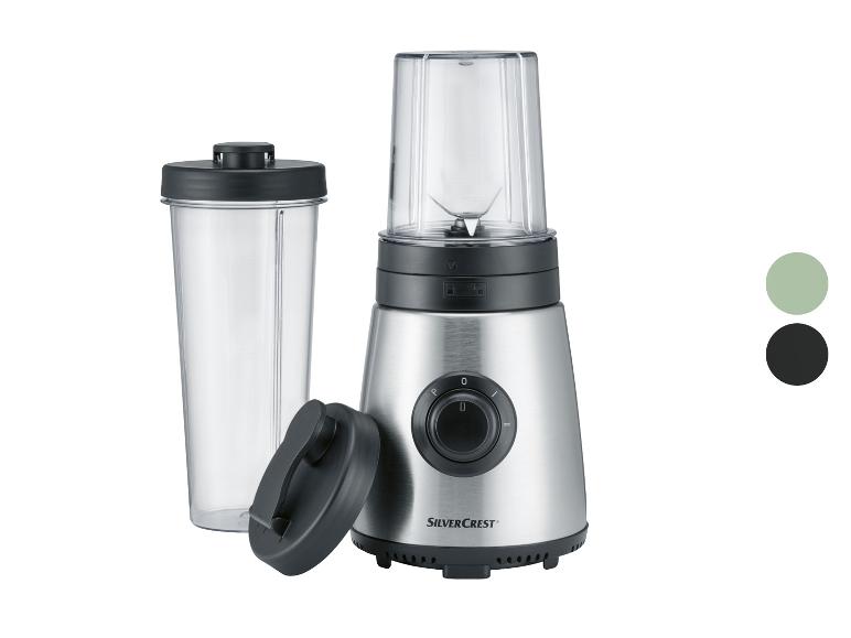 Ein silberfarbener SilverCrest Mixer mit Glasbehälter und To-Go-Becher.