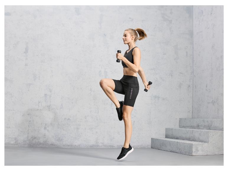 Eine Frau in schwarzer Sportbekleidung mit Jettie Sport Shorts trainiert mit Hanteln.