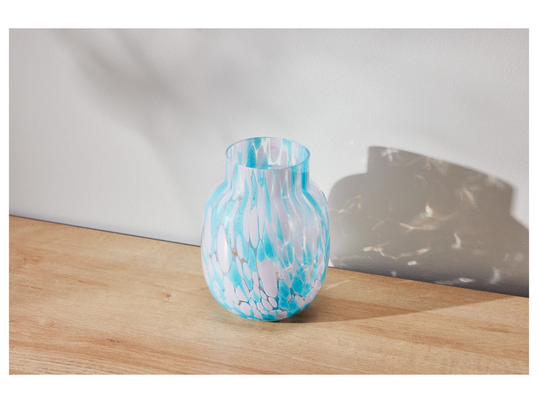 Eine blaue und weiße Vase mit Marmormuster auf einem Holztisch.