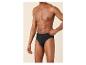 Mann in schwarzer Unterhose, Hand am Bund, vor beigem Hintergrund.