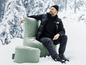 Ein Mann sitzt in einem grünen Sitting Point Sessel im Schnee.