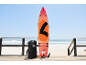 Orangefarbenes Paddleboard mit Zubehör und Tasche auf einem Holzsteg am Strand.
