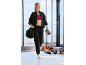 Frau in schwarzem Trainingsanzug und rotem Sport-BH, mit Sporttasche und Wasserflasche.