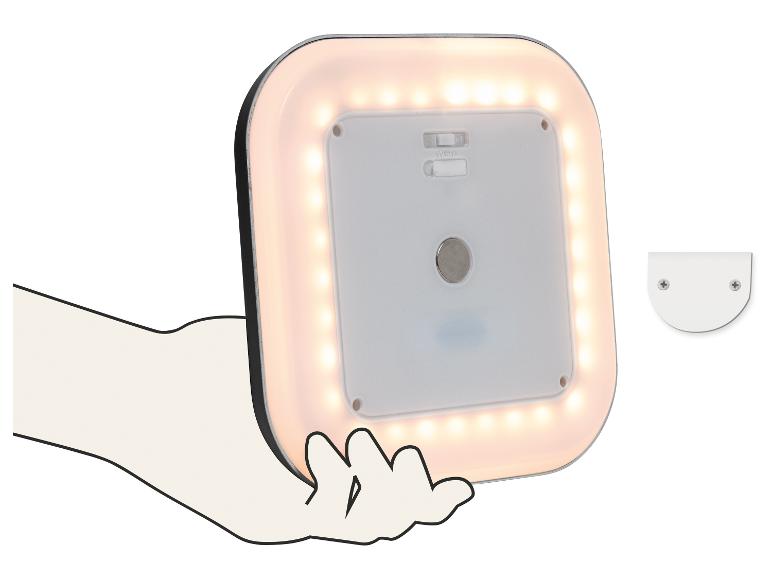 Quadratische LED-Lampe mit warmweißem Licht, in der Hand gehalten, mit einer Montagehalterung daneben.