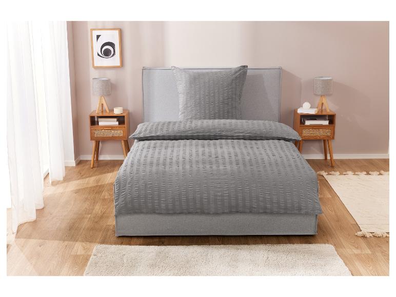Graues, strukturiertes Bettwäsche-Set und Bett mit Nachttischen.