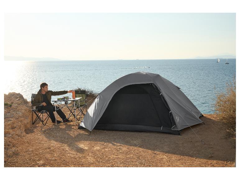 Mann campt am Meer mit einem CRIVIT Zelt, Klappstühlen und einem Tisch.