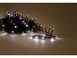 Weiße LED-Lichterkette auf einem Tannenzweig, mit verstreuten Lichtern auf dem Boden.