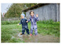 Zwei Kinder in Regenkleidung spielen in einer Pfütze.
