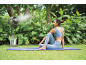 Frau macht Yoga im Freien mit einem Nebelventilator zur Kühlung.