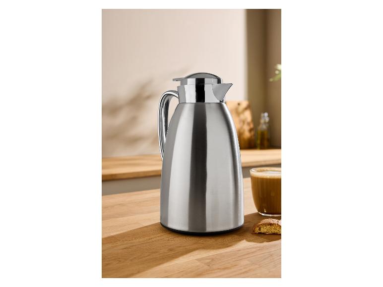 Edelstahl-Thermoskanne auf einer Holztheke mit Kaffee und einem Keks.
