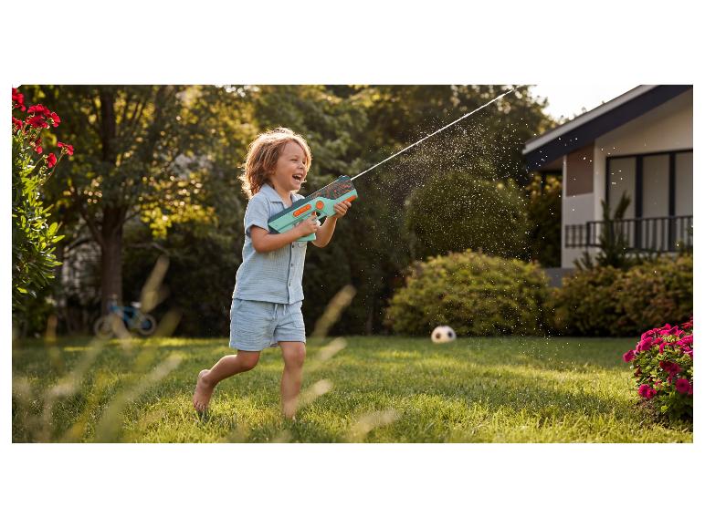 Glückliches Kind spielt mit einer Wasserpistole im Garten.