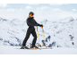 Frau im schwarzen Skianzug, Helm und Skibrille fährt Ski auf einer verschneiten Piste.