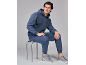Mann in blauem Kapuzenpullover und passender Hose, sitzt auf einem Hocker.