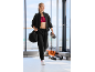 Eine Frau im schwarzen Trainingsanzug und rotem Sport-BH geht im Fitnessstudio.
