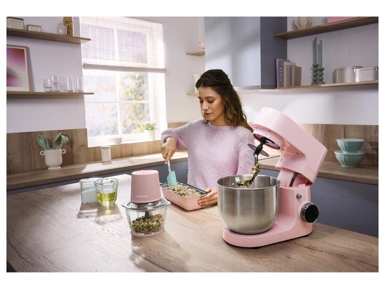 Frau kocht in der Küche mit rosa Küchenmaschine und Zerkleinerer.