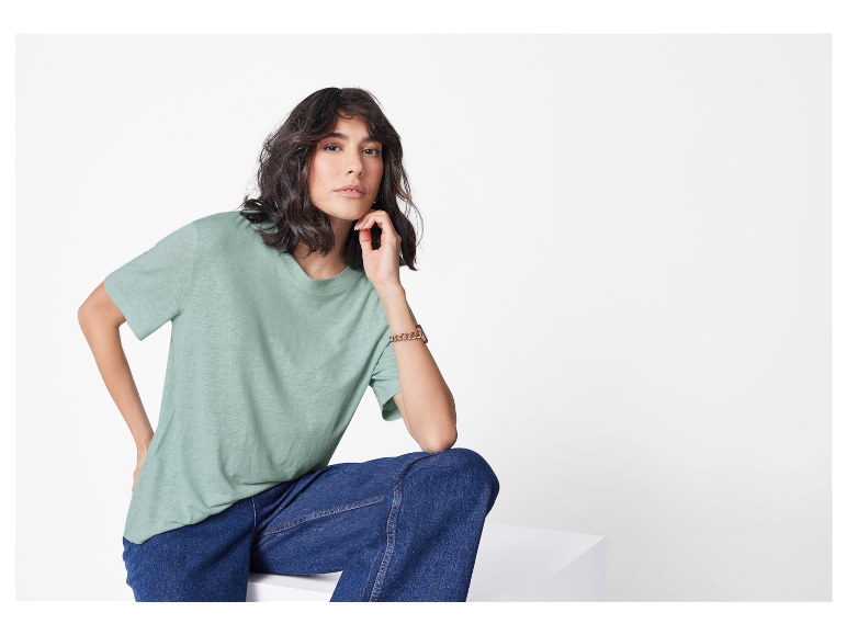 Frau modelliert ein hellgrünes T-Shirt und Jeans.