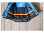Eine blaue Winterjacke mit orangenen Details und einem Namensschild.