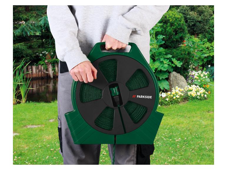 Ein Mann hält eine grüne Parkside Gartenschlauchrolle.