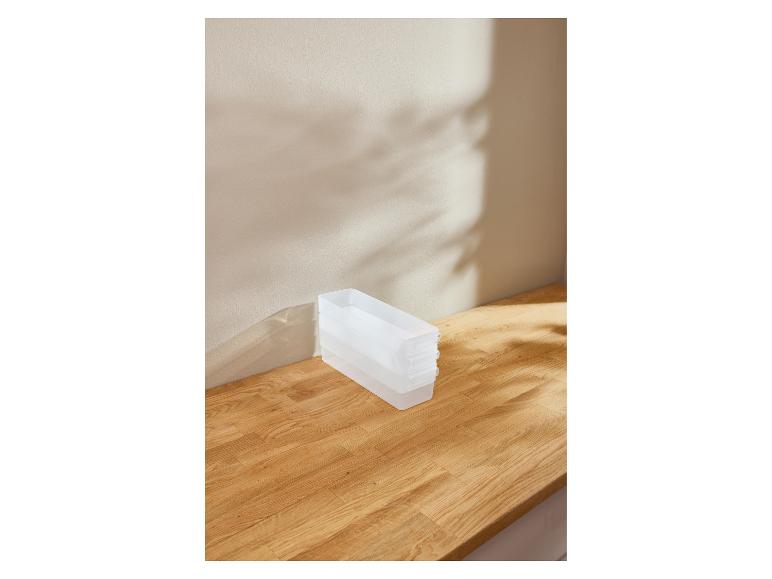 Transparente Plastik-Organizer gestapelt auf einer Holzoberfläche mit Schatten.