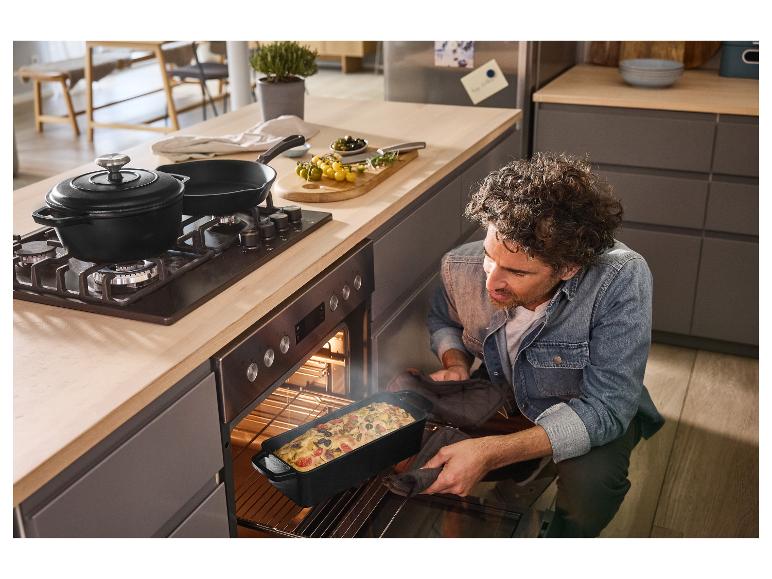 Ein Mann nimmt frisch gebackenes Brot in einer SILVERCREST® Gusseisen-Backform aus dem Ofen.