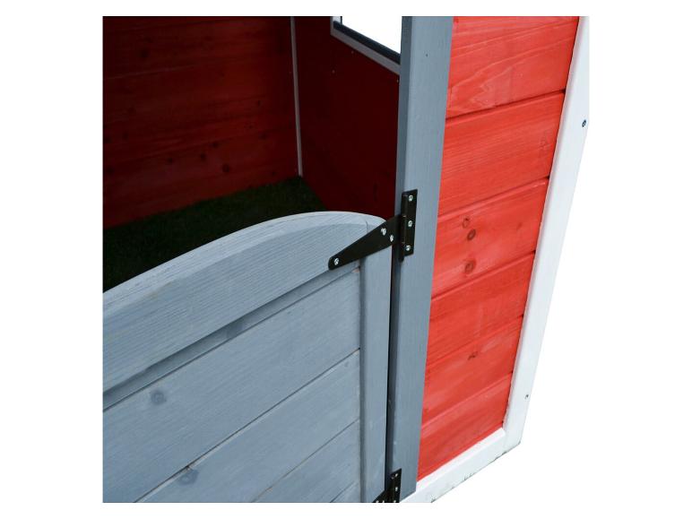 Innenansicht eines roten Holzspielhauses mit grauer Tür und grünem Boden.