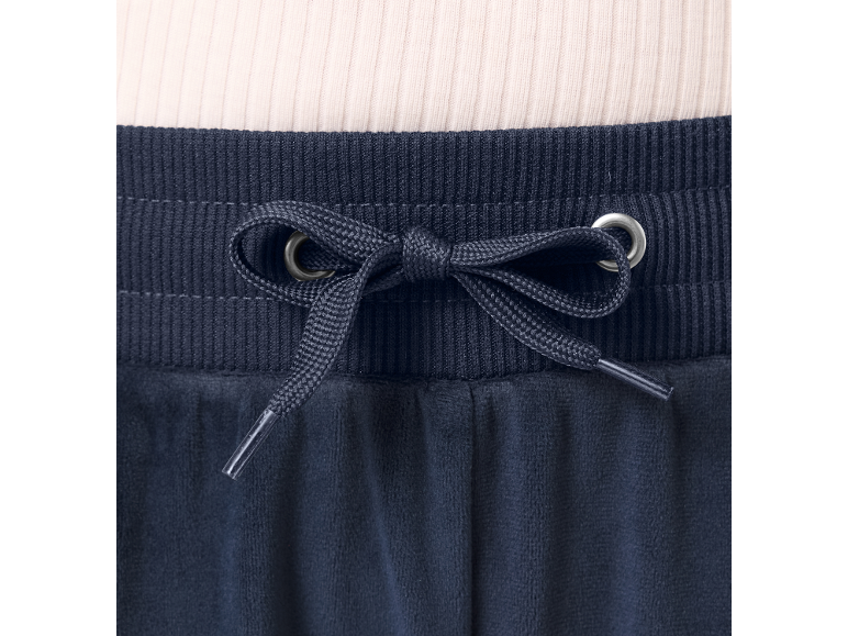 Nahaufnahme einer marineblauen Velours-Jogginghose mit Kordelzug und hellem Rippoberteil.