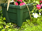 Grüner Blumenkasten mit Rollen für Blumen.