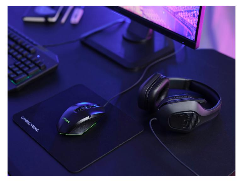 Gaming-Maus und Kopfhörer auf einem Pad, daneben Tastatur und Monitor.