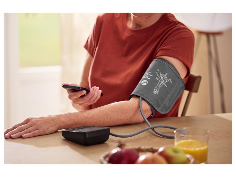 Eine Person misst ihren Blutdruck mit einem digitalen Blutdruckmessgerät.