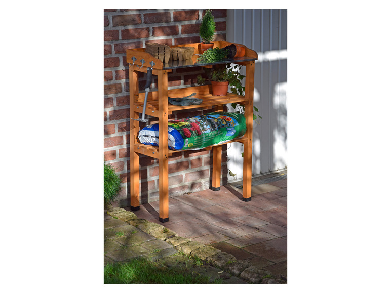 Ein Holz-Pflanzenregal mit Werkzeug, Erde und Pflanzen.