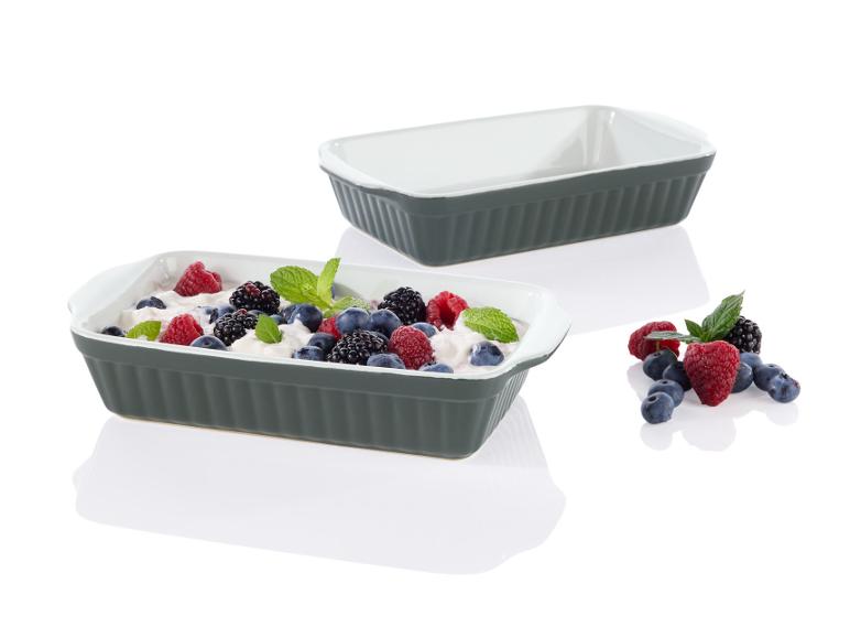 Zwei graue Auflaufformen mit weißem Innenleben, gefüllt mit Joghurt und Beeren.