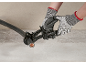 Eine Person schneidet ein dickes Kabel mit einer Ratschen-Kabelschere und trägt Schutzhandschuhe.