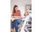 Ein Baby sitzt in einem Stokke Tripp Trapp Hochstuhl an einem Tisch mit einem Erwachsenen.