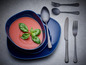 Tomatensuppe in einer blauen Schüssel mit schwarzem Besteck