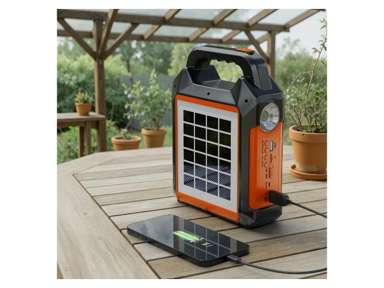 Schwarz-oranges tragbares Solarladegerät mit einem ladenden Telefon auf einem Holztisch.