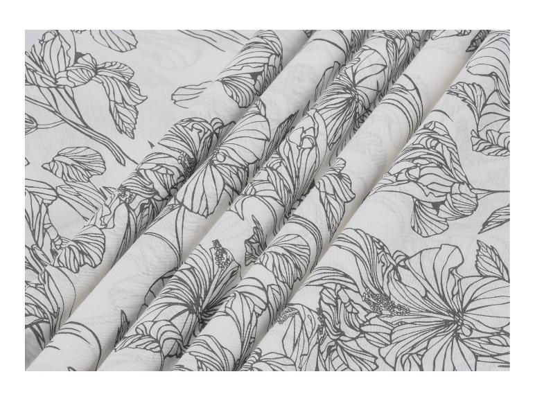 Weißer Stoff mit schwarzem Blumenmuster, in Falten drapiert.