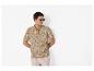 Mann in einem Polohemd mit Blattmuster und hellen Shorts, trägt Sonnenbrille