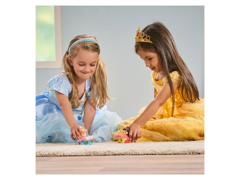 Zwei Mädchen in Prinzessinnenkleidern spielen mit Spielzeug auf einem Teppich.