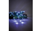Tannenzweige mit weißen Weihnachtsleuchten auf dunklem Hintergrund.